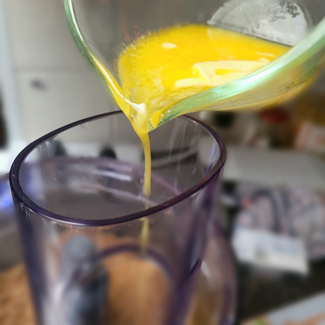 Pouring melted butter into the food processor.